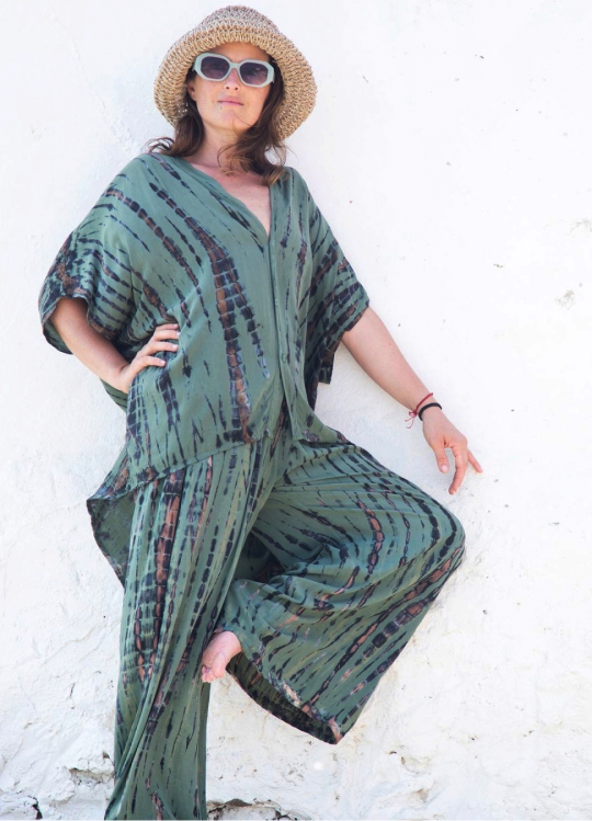 Romina, creadora de Indico Concept, posa llevando una blusa y un pantalón tie dye verde.